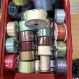 Two boxes of unused and part used reels of mainly satin ribbons of varying colours and widths