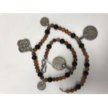 An amber beaded necklace with Eastern silver coin and pendant decoration