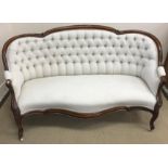 A Victorian walnut framed show frame sofa, with moulded and foliate carved decoration,