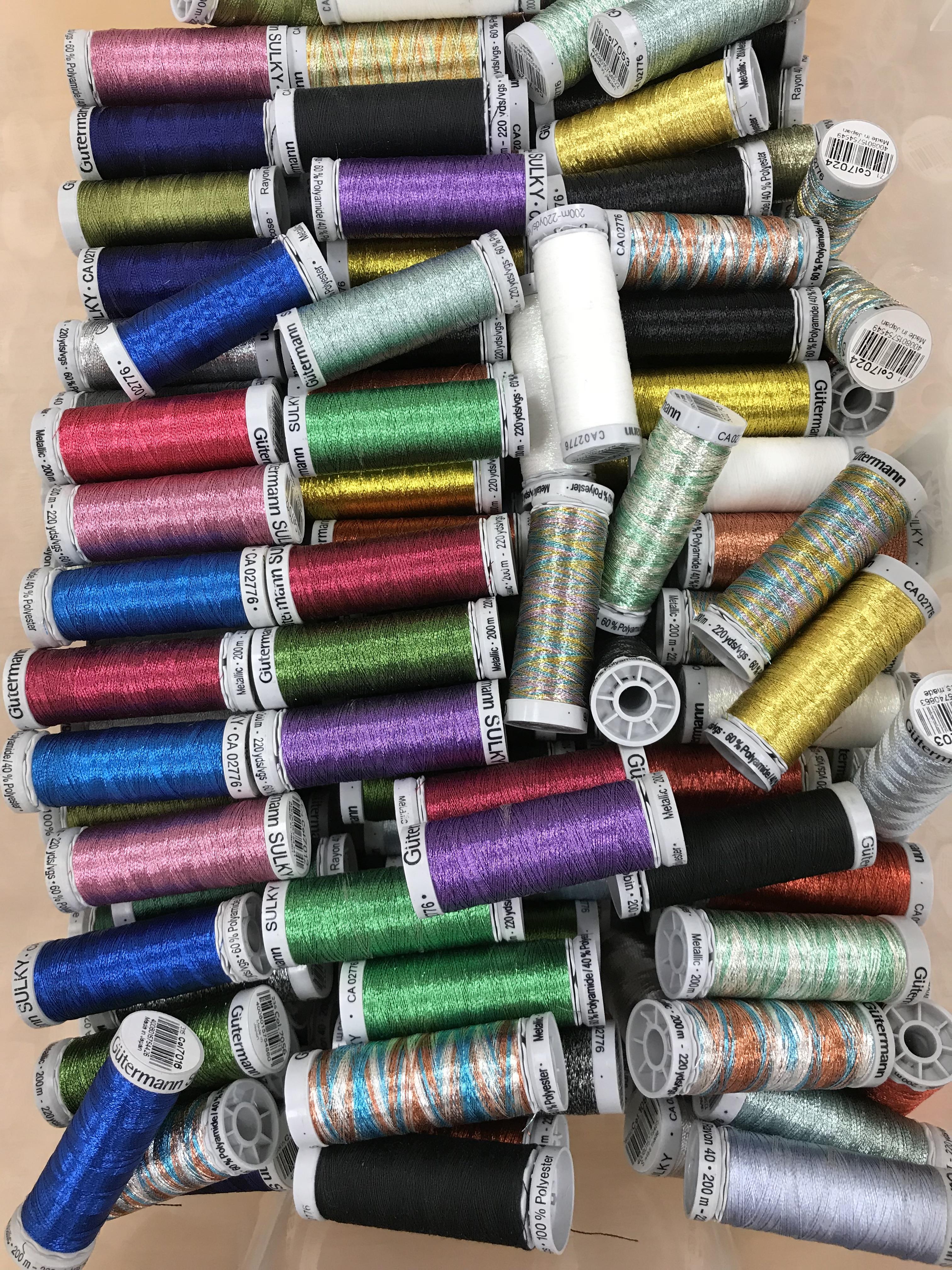 A box containing a large quantity of Gutermann machine embroidery thread both plain and metallic