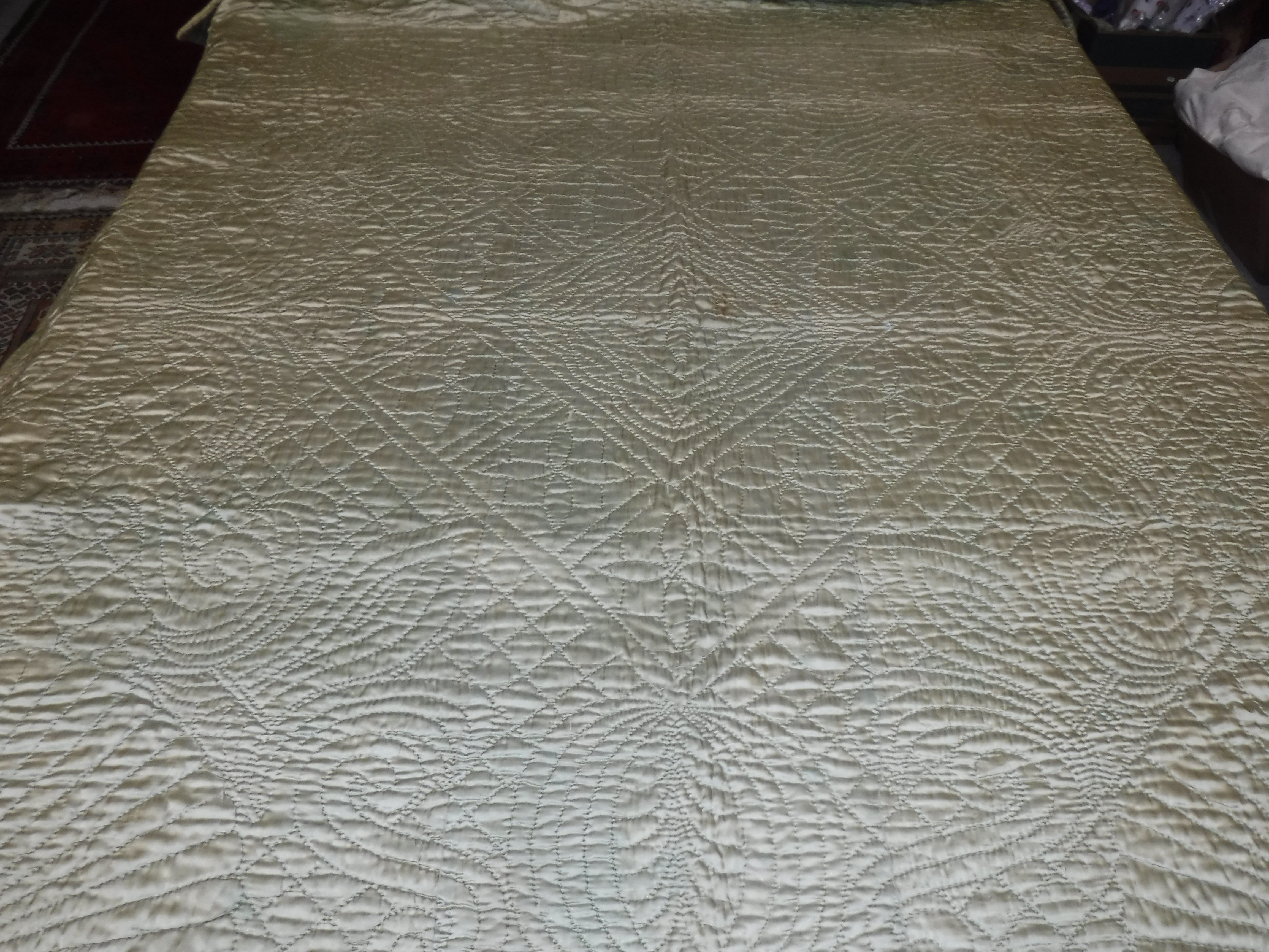 A circa 1950 sateen quilted bed cover with stylised sunburst and scrolling decoration approx.