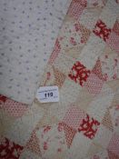 An early 20th Century patchwork style quilt with printed patchwork design in reds,