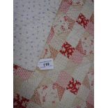 An early 20th Century patchwork style quilt with printed patchwork design in reds,