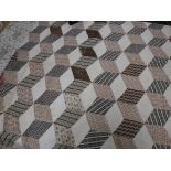 An early 20th Century tumbling blocks pattern quilt of large proportions in brown,