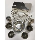 A collection of silver wares to include a pair of four slice toast racks, two pairs of silver salts,