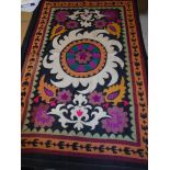 A 20th Century Middle Eastern table cover with stylised foliate decoration on a black ground 131 cm