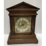 A circa 1900 oak cased mantel clock of architectural form,
