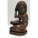 WITHDRAWN A Balinese carved treen ware figure of "Kneeling woman adjusting her headdress",