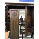 A late Victorian walnut wardrobe compactum with foliate carved doors flanking a central mirrored