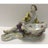 A Meissen figural salt as a man in 18th Century dress beside a large boat shaped dish with floral