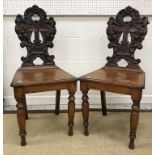 A pair of Victorian carved oak panel seated hall chairs,