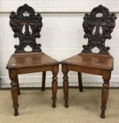 A pair of Victorian carved oak panel seated hall chairs,