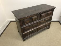 A 17th Century oak chest, the plank top over a bank of six short drawers with brass drop handles,