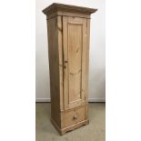 A slim pine cupboard with single panel door enclosing three shelves over a single drawer with