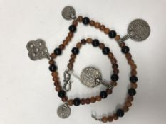 An amber beaded necklace with Eastern silver coin and pendant decoration