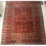 A Hatchli Bokhara rug, the central panel set with black design on a red ground within a stepped red,