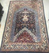 A Persian carpet of Mihrab style design, the central panel with foliate decoration on a blue,