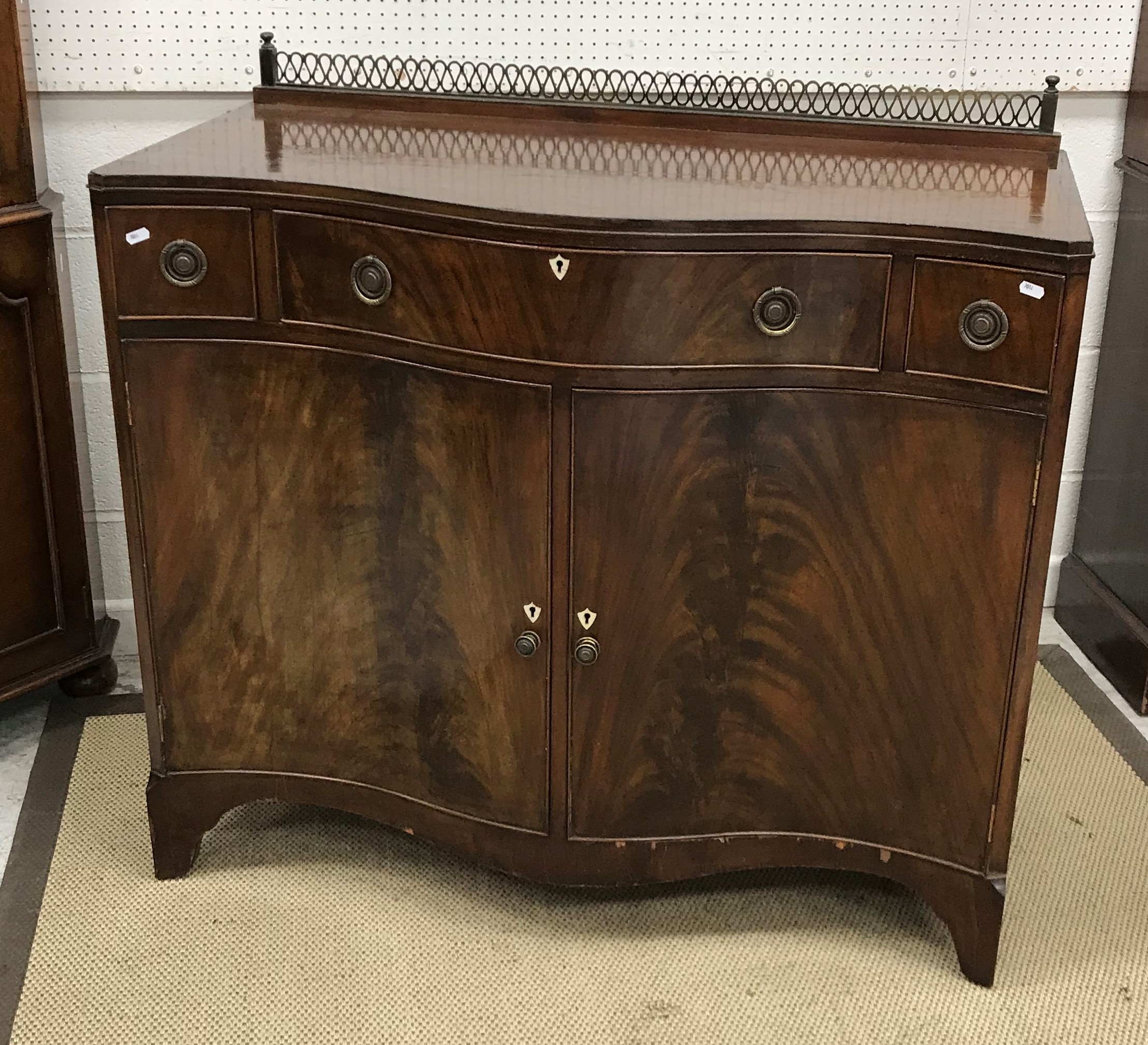 An Edwardian mahogany and cross banded serpentine fronted side cabinet with single long and two
