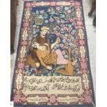 A Kashmir pictorial rug depicting a couple drinking beneath floral decorated trees on a blue ground