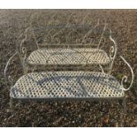A pair of cream painted metal garden benches with love heart decoration to backs and lattice work