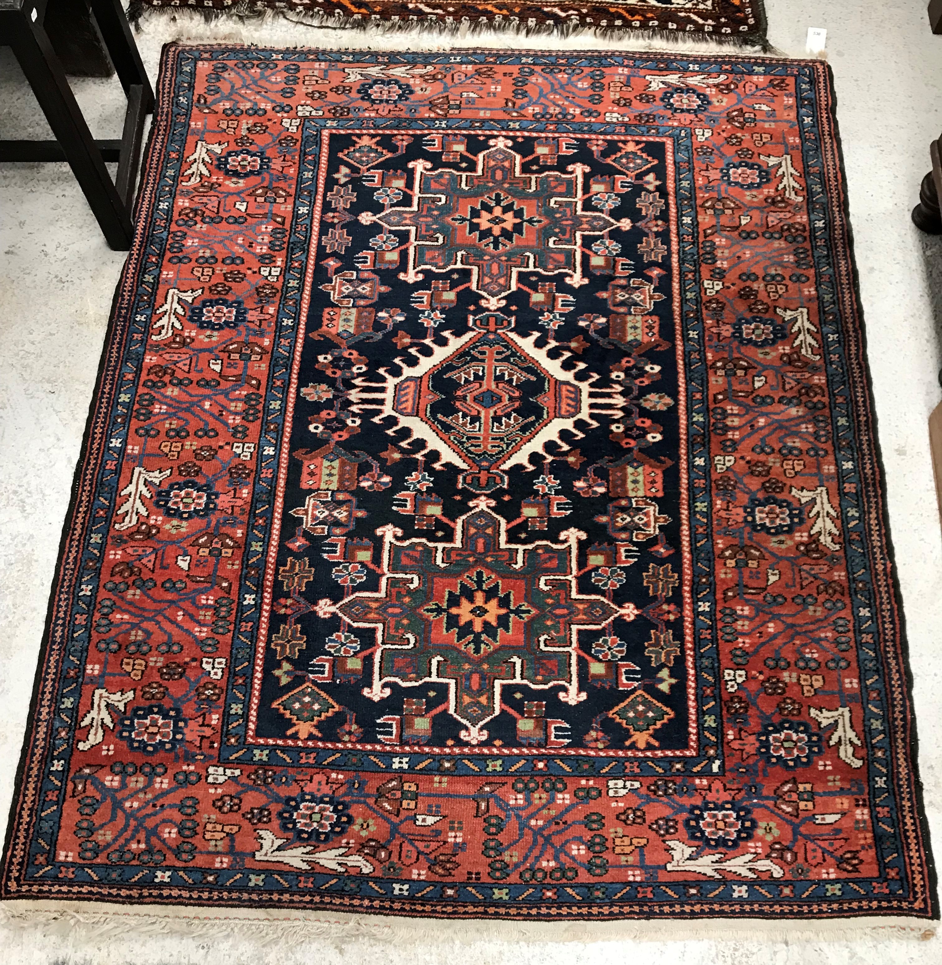 A Persian rug, the central panel set with three medallions on a dark blue ground,