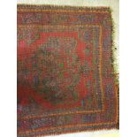 A Donegal rug, the central panel set with stylised cross medallion on a red ground,