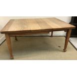 An Edwardian oak rectangular extending dining table on square tapered legs to splayed feet and