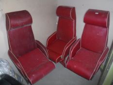 A collection of three red leatherette covered aeroplane seats,