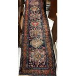 A vintage Heriz runner, the central panel set with repeating medallions on a dark blue ground,