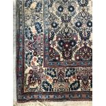 A pair of Persian rugs, the central panel set with repeating floral motifs on a cream ground,