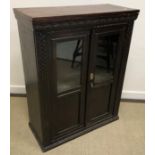 A carved oak part glazed two door cupboard in the Gothic style,