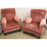 A pair of circa 1900 salmon pink upholstered scroll arm chairs on turned tapering legs to brass