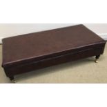 A modern brown leather upholstered drawing room stool of rectangular form raised on turned ebonised