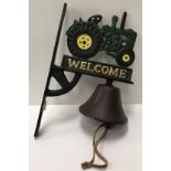 A modern cast metal and painted wall mounted bell with tractor decoration and inscribed "Welcome"