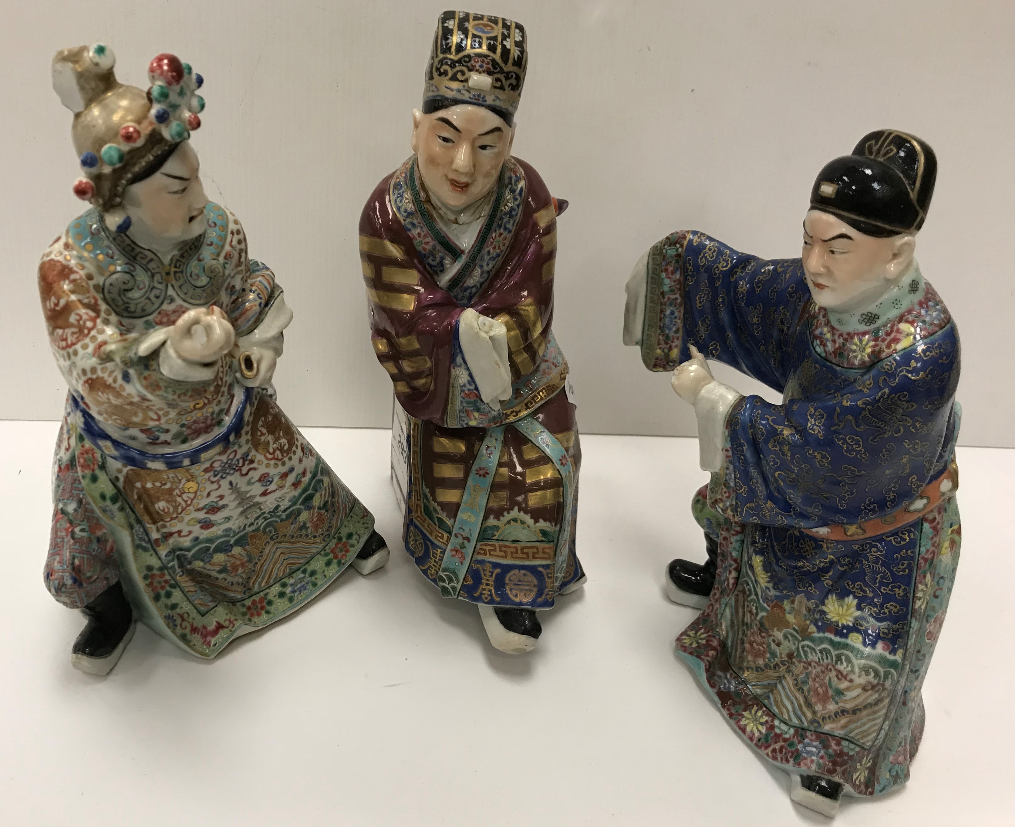 A set of three 19th Century Chinese polychrome decorated figures, one seated, one bearing sword,