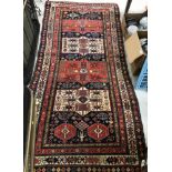 A vintage Caucasian rug, the central panel set with repeating medallions on a blue ground,