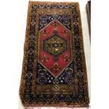 A Caucasian rug, the central panel set with lozenge shaped medallion on a red and blue ground,