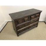 A 17th Century oak chest, the plank top over a bank of six short drawers with brass drop handles,