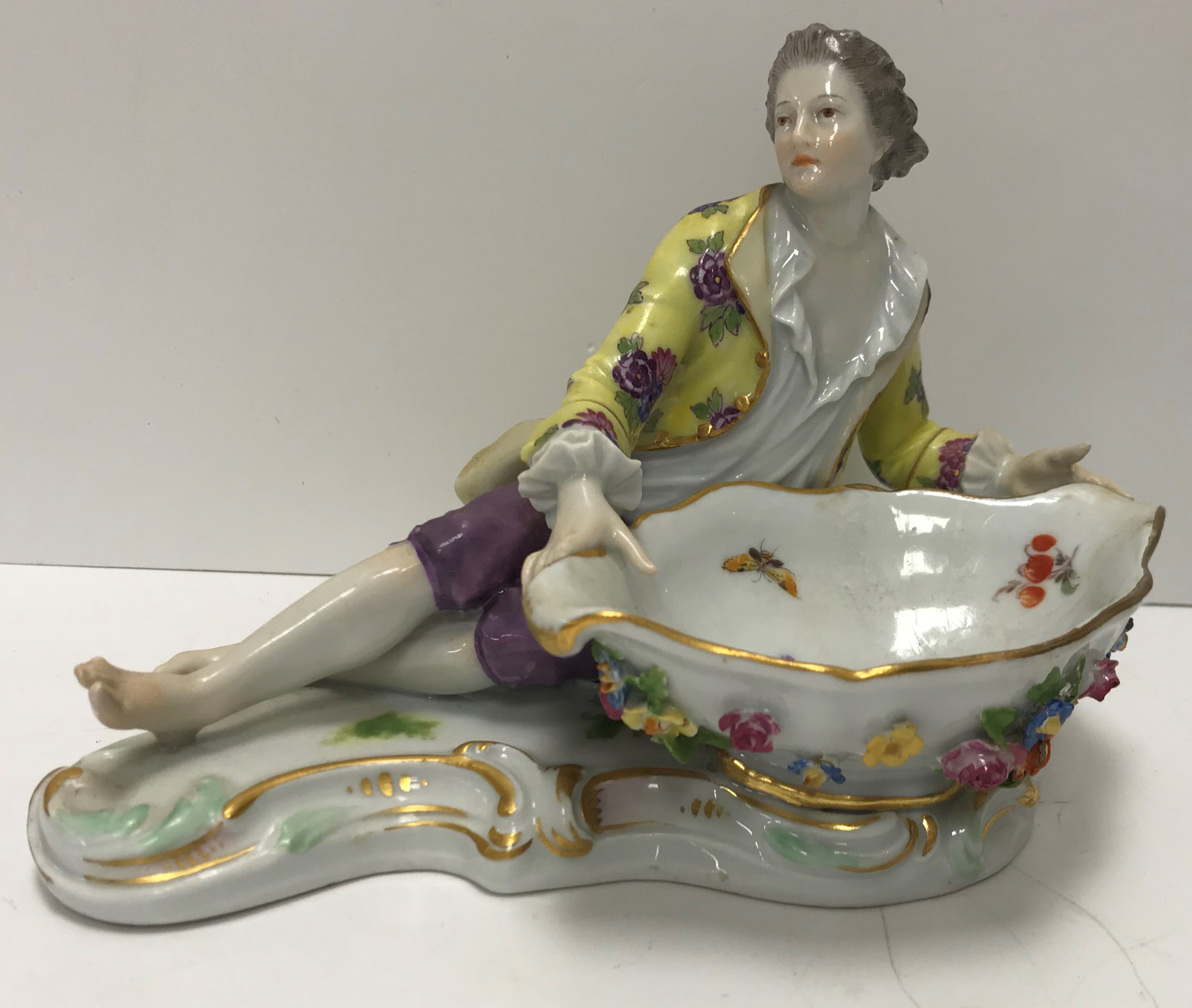 A Meissen figural salt as a man in 18th Century dress beside a large boat shaped dish with floral