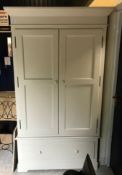 A modern cream painted pine wardrobe with two doors enclosing a hanging space and adjustable shelf