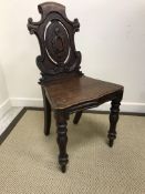 A pair of Victorian oak panel seated hall chairs with pierced medallion backs on baluster turned