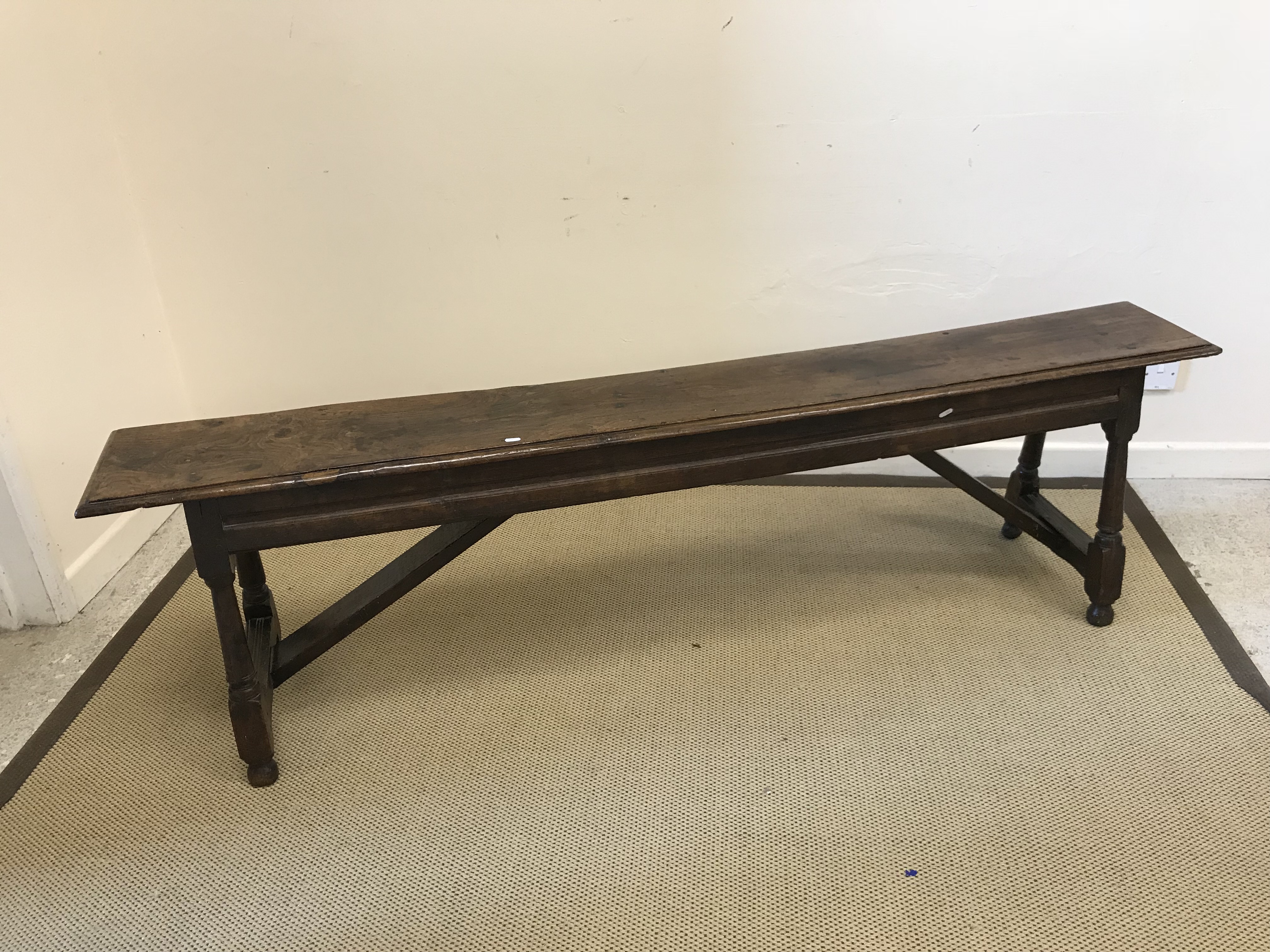 An 18th Century oak stool, the single plank top with moulded edge above a moulded frieze, on turned,