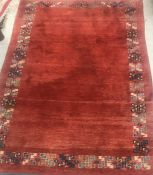 A Persian rug, the plain red ground set