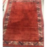 A Persian rug, the plain red ground set