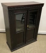 A carved oak part glazed two door cupboa