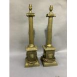 A pair of brass classical column table lamps with applied face masks and on square base, 64cm high