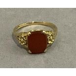 A cornelian dress ring, the quatrefoil seal cut stone claw set flanked by foliate bifocated