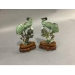 A pair of Chinese polished hardstone figures of an egret and cat in the branches of a pine tree,