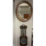 An Edwardian oval oak wall mirror with bevelled glass together with a 1920's oak aneroid barometer