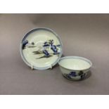 A Nanking cargo tea bowl and saucer painted in blue and white with a pagoda island river